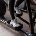 Young woman in leggings in sports sneakers does cardio training on a stepper simulator in the gym. Girl burns calories.