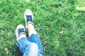 Young woman legs in sport shoes sneakers of blue suede, sitting on the grass lawn in park Royalty Free Stock Photo