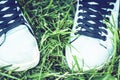 Young woman legs in sport shoes sneakers of blue suede, standing on the grass lawn in park Royalty Free Stock Photo