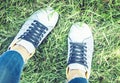 Young woman legs in sport shoes sneakers of blue suede, standing on the grass lawn in park Royalty Free Stock Photo