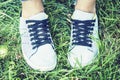 Young woman legs in sport shoes sneakers of blue suede, standing on the grass lawn in park Royalty Free Stock Photo