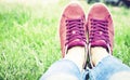 Young woman legs in sport shoes sneakers of pink suede, sitting on the grass lawn in park Royalty Free Stock Photo