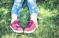 Young woman legs in sport shoes sneakers of pink suede, sitting on the grass lawn in park Royalty Free Stock Photo