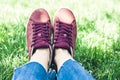 Young woman legs in sport shoes sneakers of pink suede, sitting on the grass lawn in park Royalty Free Stock Photo