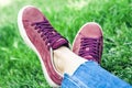 Young woman legs in sport shoes sneakers of pink suede, sitting on the grass lawn in park Royalty Free Stock Photo