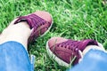 Young woman legs in sport shoes sneakers of pink suede, sitting on the grass lawn in park Royalty Free Stock Photo