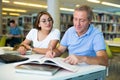 Young woman librarian helps an elderly man find the necessary information in laptop Royalty Free Stock Photo