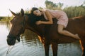 Woman lies astride a horse at river