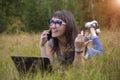 Young woman lies on the grass with a laptop and speaks emotionally on the phone Royalty Free Stock Photo