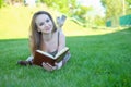 Young woman lies on green grass and reads book in the city park. Royalty Free Stock Photo