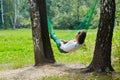 Young woman lies in hammock suspended between birches