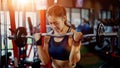 Young woman lifting up the heavy barbell in fitness gym