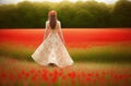 A young woman in a light translucent dress walks through a flowering field. Back view