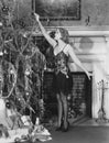 Young woman lighting candles on Christmas tree