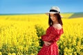 Young brunette girl in a red light dress on yellow field