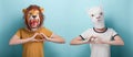 Young woman in lion and alpaca mask show love heart affection hand gesture
