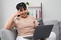 Young woman listen to music with headphone and use laptop computer for study, work, relax sitting on the sofa at home