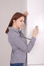 Young woman listening closed fridge with stethoscope Royalty Free Stock Photo