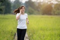 Woman listening music on earphones while running on wooden path in field