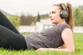 Young woman listening music on headphones while lying on grass Royalty Free Stock Photo