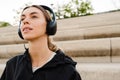 Young woman listening music with headphones while standing outdoors Royalty Free Stock Photo