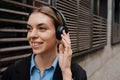 Young woman listening music with headphones while walking at city street Royalty Free Stock Photo