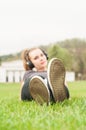 Young woman listening music lying cross-legged on grass Royalty Free Stock Photo