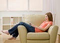 Young woman listening to mp3 player on armchair Royalty Free Stock Photo