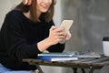 Young woman listening to music on headphone, typing text message, chatting online on mobile phone Royalty Free Stock Photo
