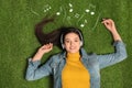 Young woman listening to music through headphones on green grass Royalty Free Stock Photo