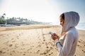 Young woman is listening to the music on the phone before jogging on the beach at the sunrise