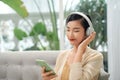 Young woman listening to music while relaxing on sofa at home Royalty Free Stock Photo