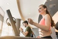 Young woman listening to music while running on a modern treadmill