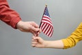 Young woman and little child holding american flag on grey background. Independence Day concept. National holiday Royalty Free Stock Photo