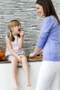 Young woman and little girl eating carrots in the kitchen Royalty Free Stock Photo