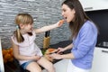 Young woman and little girl eating carrots in the kitchen Royalty Free Stock Photo