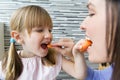 Young woman and little girl eating carrots in the kitchen Royalty Free Stock Photo