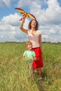 Young woman and little girl plays kite on meadow Royalty Free Stock Photo