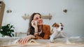 Beautiful single woman lying on bed, petting her dog, and making phone call. Young woman living alone in apartment Royalty Free Stock Photo