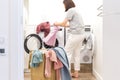 Young Woman loading washing machine and a Basket Full Of Dirty Clothes In Laundry Room Royalty Free Stock Photo