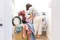 Young Woman loading washing machine and a Basket Full Of Dirty Clothes In Laundry Room Royalty Free Stock Photo