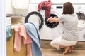 Young Woman loading washing machine and a Basket Full Of Dirty Clothes In Laundry Room Royalty Free Stock Photo