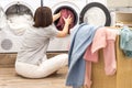 Young Woman loading washing machine and a Basket Full Of Dirty Clothes In Laundry Room Royalty Free Stock Photo