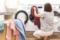 Young Woman loading washing machine and a Basket Full Of Dirty Clothes In Laundry Room Royalty Free Stock Photo