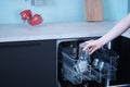 Young woman loads the dishwasher with dirty dishes Royalty Free Stock Photo