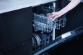 Young woman loads the dishwasher with dirty dishes Royalty Free Stock Photo