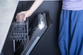 Young woman loads the dishwasher with dirty dishes Royalty Free Stock Photo