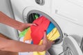Young woman loads the laundry in the washing machine from the laundry basket before washing. Royalty Free Stock Photo