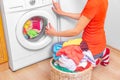 Young woman loads the laundry in the washing machine from the laundry basket before washing. Royalty Free Stock Photo