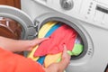 Young woman loads the laundry in the washing machine from the laundry basket before washing. Royalty Free Stock Photo